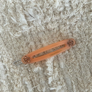 Detail van een oranjeroze hars haarklem met strass steentjes en een zilveren metalen basis