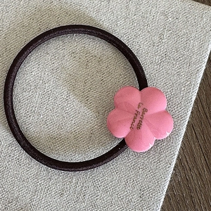Détail de l'élastique à cheveux fleur en résine rose avec logo doré Barrette la France