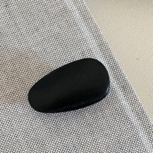 Detailed view of a black matte metal teardrop hair clip on a textured fabric surface