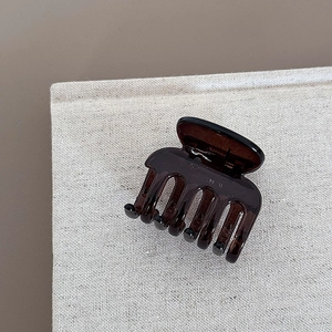 Detail of glossy transparent amber hair claw clip on minimalist textured background