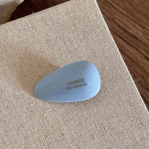 Close-up of sky blue acetate teardrop hair clip with golden France Handmade text