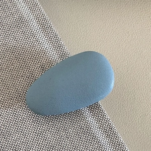 Detailed macro view of matte light blue oval hair clip with textured leather finish