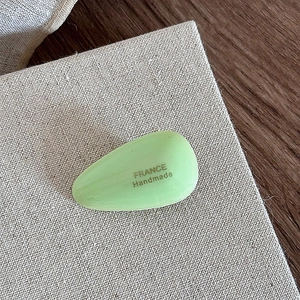 Macro shot of light green acetate water drop hair clip with gold France Handmade logo
