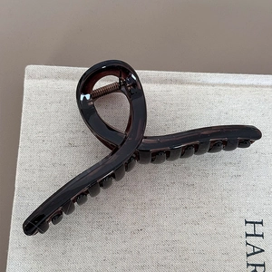 Detail of a dark brown translucent shark hair clip with a glossy finish and spiral design