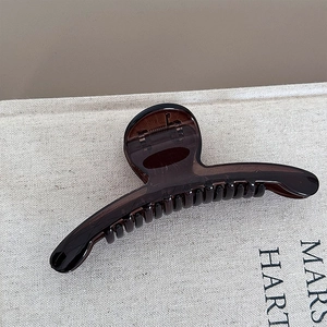 Detail view of transparent brown hair claw clip with elegant curved lines and glossy finish