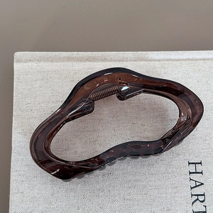 Detailed macro view of the wave-shaped amber brown hair claw clip with its metal spring