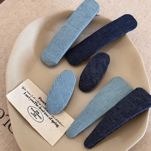 Detail of denim fabric hair clips in oval and rectangular shapes on a ceramic plate
