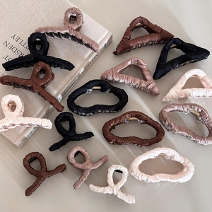 Minimalist fabric wrapped shark hair clips in assorted earth tones on an aesthetic background