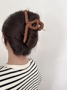 Brown fabric wrapped shark hair clip for women styled in dark hair on white background