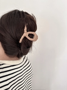 Detail view of large fabric-wrapped hair claw clip in beige on a deep brown hair bun