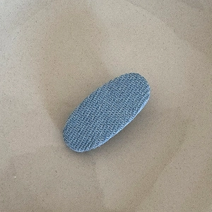 Detailed view of the oval denim fabric hair clip with a vintage blue woven texture
