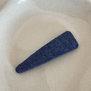 Detail view of dark blue denim fabric texture on rectangular vintage snap hair clip