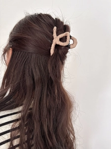 Detail view of coffee fabric wrapped hair claw clip on medium-long hair for styling
