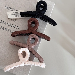 Close-up of elegant pleated fabric hair claws in assorted neutral colors with silk texture