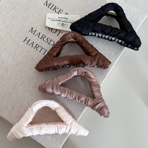 Macro detail of fabric wrapped shark hair clips in black, brown, pink, and cream colors