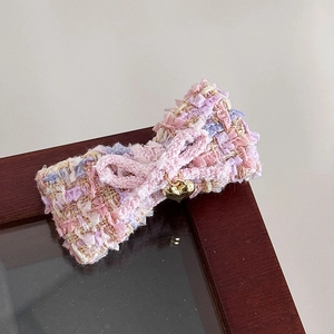 Detail der Tweed-Schleife-Haarspange in Rosa und Lila mit goldenem Herzanhänger und Häkel-Element