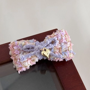 Nahaufnahme einer Haarspange mit Tweed-Schleife in Rosa-Violett und Herz-Anhänger