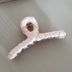 Detail view of pink satin fabric wrapped shark hair clip with soft spiral texture