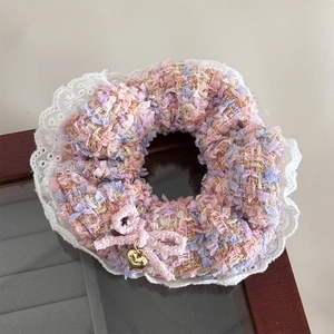 Detail von Haargummi aus Tweed in Pink und Lila mit Spitzenkante und Herz-Anhänger