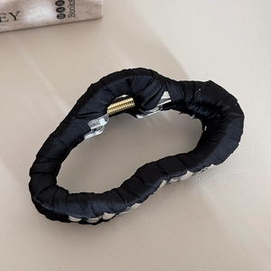 Detail of black fabric wrapped heart-shaped hair claw clip with metallic spring