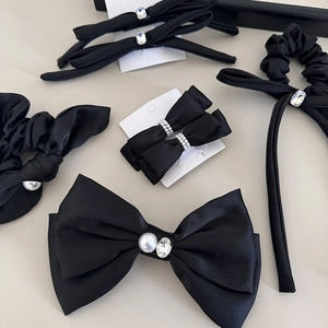 Elegant black satin bow hair clip set with white pearls and sparkling rhinestone accents