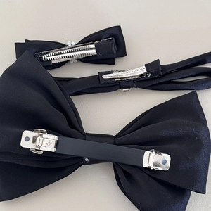 Detail of black satin bow hair clips featuring spring clip and duckbill clip fasteners