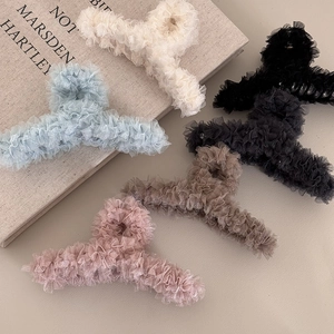 Five assorted colors of elegant lace mesh hair claw clips on a vintage book background