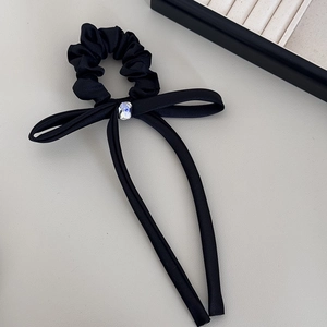 Detail of black satin hair scrunchie with long ribbon and square crystal centerpiece