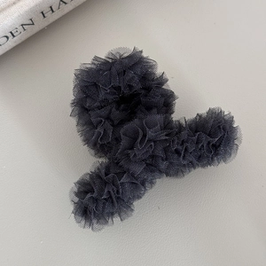 Détail de pince à cheveux élégante en résille noire avec texture plissée multicouche