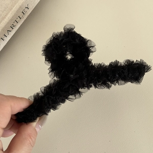 Detail of black layered lace hair claw clip with pleated mesh fabric for elegant styling