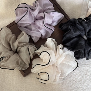 Detailed close-up of four organza hair scrunchies with elegant contrast piping detail