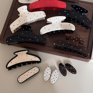 Dettaglio di pinze per capelli in acetato con strass colorati su vassoio in legno