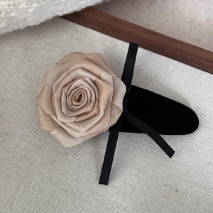 Detail of a champagne rose hair clip with vintage black velvet ribbon and gold glitter accents