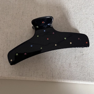 Dettaglio di strass colorati su una molletta per capelli nera lucida a squalo