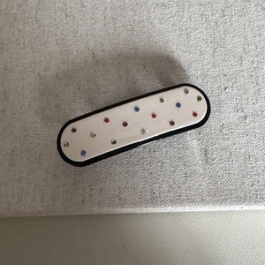 Dettaglio di strass multicolori su un fermaglio per capelli ovale in acetato dal design semplice