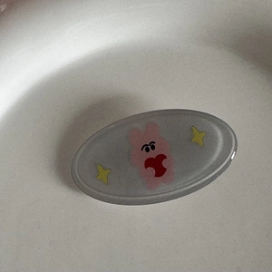 Détail de la barrette ovale en résine avec un personnage de dessin animé rose et étoiles