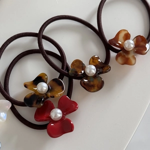 Detail of floral acetate hair ties with tortoise pattern and elegant pearl centerpiece