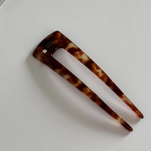 Close-up of tortoise shell U-shaped hair pin with marble pattern and small rhinestone