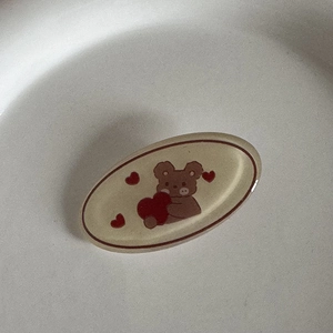 Détail d'une pince à cheveux ovale avec un ours mignon tenant un cœur rouge
