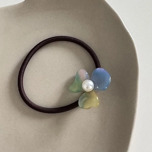 Detailed macro view of retro acetate flower hair tie with pearl center and gradient petals