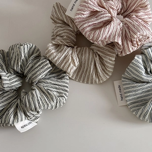 Detail of four handmade striped scrunchies in red, brown, black, and blue with cotton texture