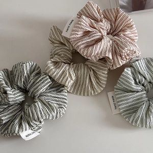 Detail of striped handmade scrunchies with woven labels on a white background