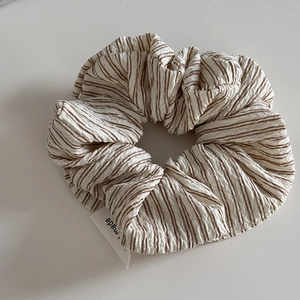 Close-up of brown and white striped seersucker scrunchie with detailed pleats and label