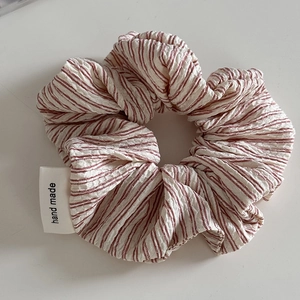 Detailed view of red and white seersucker scrunchie with handmade woven label