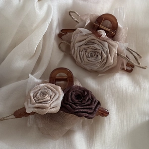 Macro detail of fabric rose hair claw clips on elegant cream satin backdrop