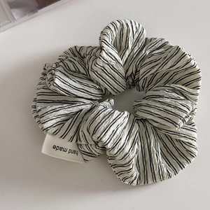 Detail of black and white striped scrunchie with handmade woven label and puckered fabric
