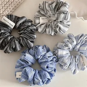 Detailed view of striped seersucker scrunchies in various colors with woven labels