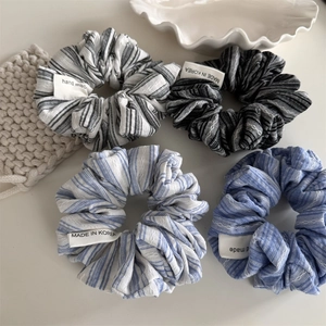 Detail of four striped handmade scrunchies with textile labels on a ceramic plate