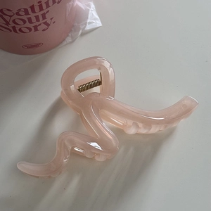 Detailed close-up of a pink wavy hair claw clip showing the durable metal spring mechanism