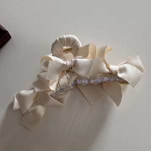Dettaglio dell'elegante molletta per capelli con fiocchi in raso beige e molla dorata
